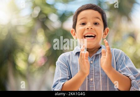 Happy, wow and boy clapping hands in in a park, excited and surprised by good news, nature and learning. Portrait, child and hands by kid face in Stock Photo