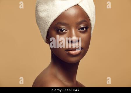 Headshot close up portrait of beautiful African American woman having healthy and clean skin tone on a beige isolated background. Stock Photo