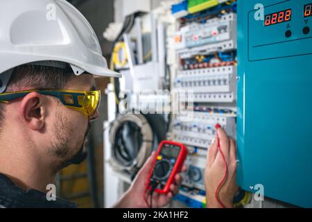 Man, an electrical technician working in a switchboard with fuses. Stock Photo