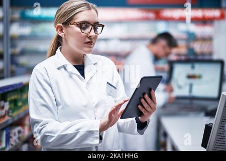 Introducing digital technology into their dispensary processes. a young pharmacist using a digital tablet in a pharmacy. Stock Photo