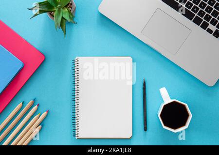 Flat lay, notepad, laptop and stationery on blue background. Stock Photo