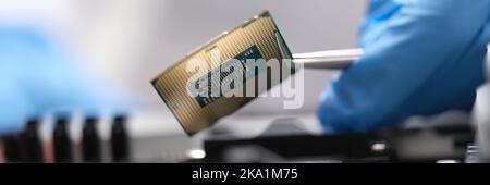 Engineer is holding microprocessor tweezers from motherboard Stock Photo