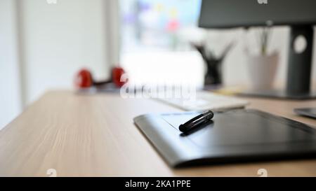 Close-up rear view image, A modern stylus tablet and stylus pen on wooden office desk. Stock Photo