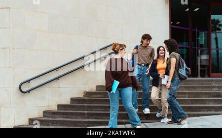 Young diverse students leaving university after lesson - Youth and education concept Stock Photo