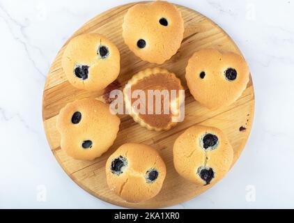 Top view freshly baked at home cupcakes of various shapes on a cutting board. Close up. Stock Photo
