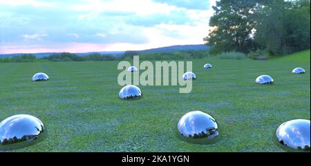 Shiny metal balls stick out of the ground on a field covered with green grass, reflecting the cloudy evening sky. 3d render. Stock Photo