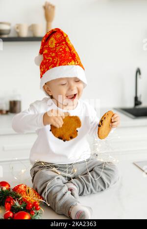 A little boy wakes up in the morning and eats Christmas cookies with milk in the kitchen laughing and happy. Christmas morning. Stock Photo
