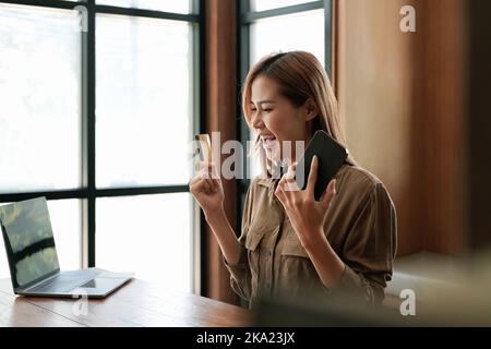 Excited woman holding credit card and using mobile phone. online shopping black friday. Stock Photo