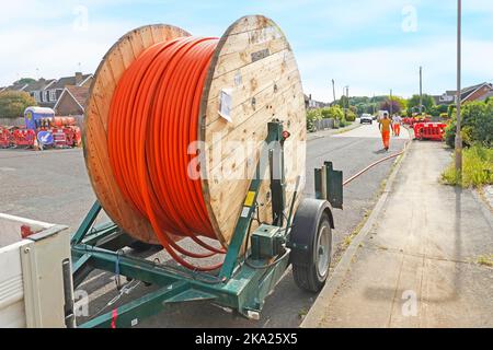 Cable drum wooden timber sides mounted on towable trailer new fibre optic broadband infrastructure supply for residential village properties Essex UK Stock Photo