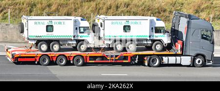 Grey Volvo hgv lorry truck driver articulated low loader trailer side view loaded transporting two Royal Airforce military ambulances UK motorway road Stock Photo