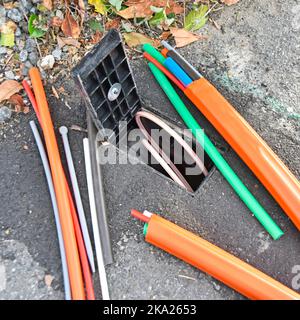 Fibre optic broadband discarded random cable offcuts beside open consumer junction box just illustration & connected customer cable ready if wanted UK Stock Photo