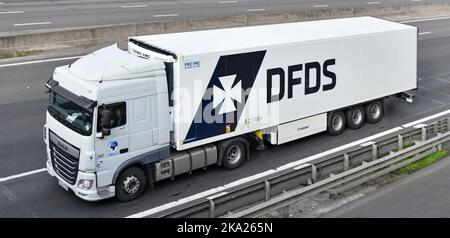 Close up side & front aerial view DAF XF hgv lorry truck driver tows DFDS articulated trailer a white commercial vehicle combination driving UK road Stock Photo