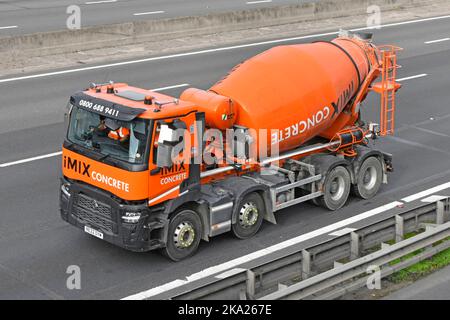 Concrete cement mixer aerial & side view revolving drum equipment mounted on hgv Renault delivery lorry truck chassis cab driving on UK motorway road Stock Photo