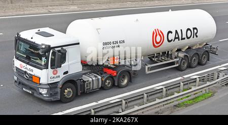 Calor Gas business logo on white Mercedes lorry truck & articulated delivery tanker trailer side & front close up view driving along UK motorway road Stock Photo