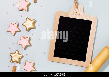Cooking holiday cookies. Food holiday composition with ginger cookies in the form of stars, covered with glaze with a dough gurney and a chalk bord wi Stock Photo