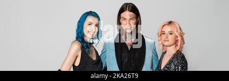 tattooed queer person and nonbinary friends hair looking at camera isolated on grey, banner,stock image Stock Photo