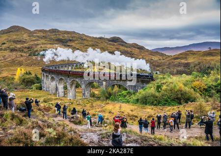 Tourists gather to wathe Jacobite scenic steam railway passing over the Glen Finnan viaduct headed by the 45407 Lancashire Fusilier steam train Stock Photo