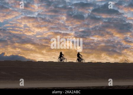People on bikes on a Dutch dike at sunset Stock Photo