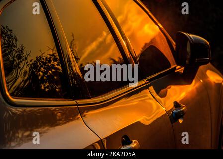 Sunset highlights on the metal surface and windows of a modern Volvo car. Stock Photo