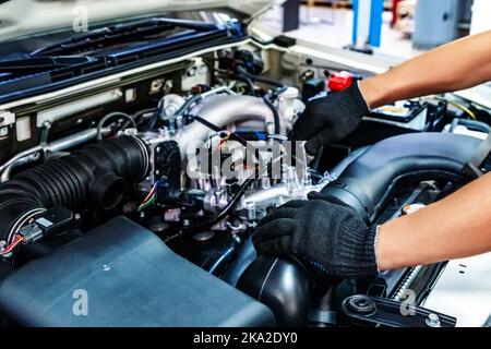 Auto mechanic working with open car hood in garage. Car repair service. Stock Photo