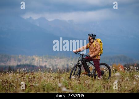 Active man on bike in the middle of autumn nature, admire mountains. Healthy lifestlye concept. Stock Photo