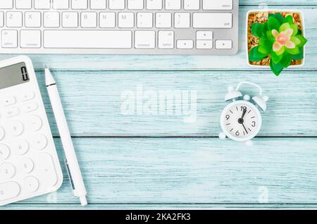 Flat lay, top view office wooden table desk. Workspace with, keyboard computer, pen, plant pot, and calculator on blue wooden background. Stock Photo