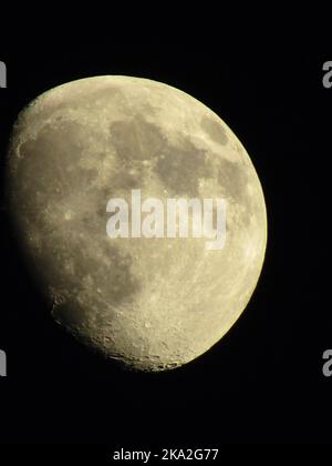 A vertical closeup of a Waxing Gibbous moon phase against a black background Stock Photo