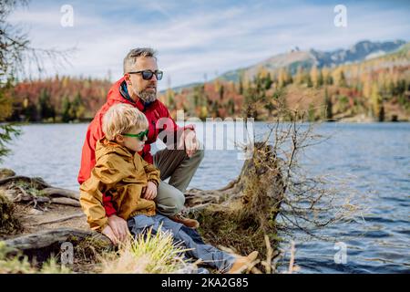 Happy father with his little son, resting near lake in mountains. Stock Photo