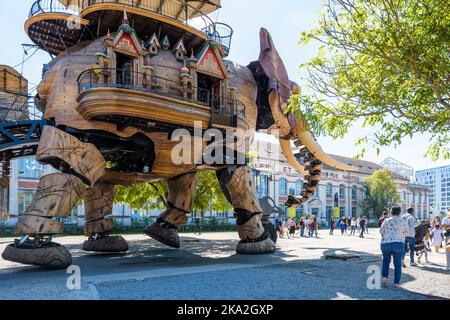 The Great Elephant giant puppet, part of the Machines of the Isle of Nantes tourist attraction, wanders amid onlookers along the shipyards building. Stock Photo