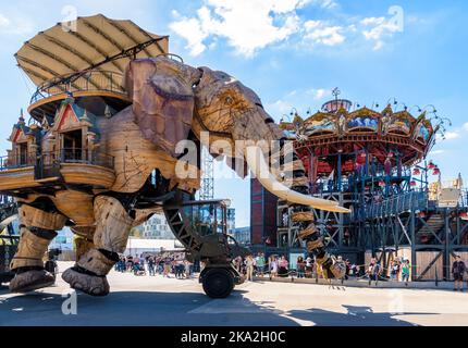 The Great Elephant giant puppet, part of the Machines of the Isle of Nantes tourist attraction, in front of the Marine Worlds Carousel. Stock Photo