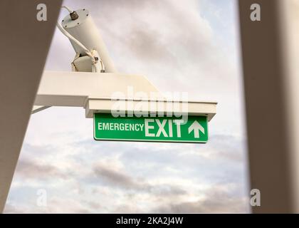 Emergency exit sign green with white text and cctv camera above. Stock Photo