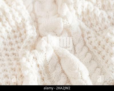 Hand made cable-knit sweater sweater. Texture of warm knitted fabric with pattern. White crumpled cardigan. Cozy autumn outfit for snuggle weather. Stock Photo
