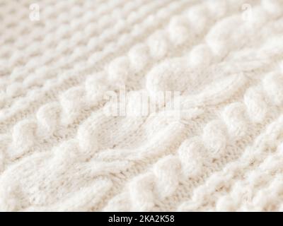 Hand made cable-knit sweater sweater. Texture of warm knitted fabric with pattern. White cardigan. Cozy autumn outfit for snuggle weather. Stock Photo
