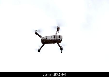 A low-angle shot of a drone flying in the air against a clear sky Stock Photo