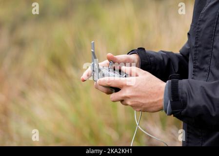 A closeup shot of a man's hand controlling the drone using remote control Stock Photo