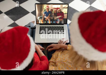 Diverse couple having christmas video call with diverse family Stock Photo