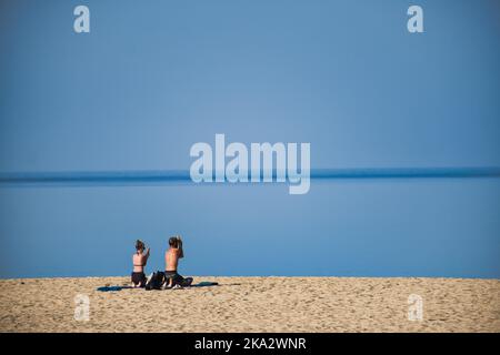 Young couple doing yoga on the morning in front of a peaceful sea Stock Photo