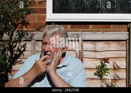 Senior man in pain with toothache. Holding his jaw in agony. Stock Photo