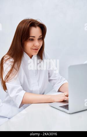 female doctor in white medical uniform using laptop Stock Photo