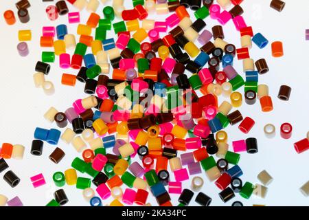 Multi-coloured hama beads scattered on white background Stock Photo