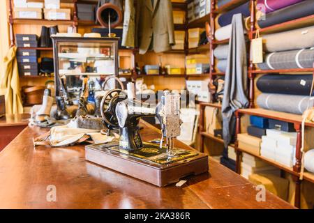 Singer sewing machine on the table inside an old fashioned tailor's shop. Stock Photo