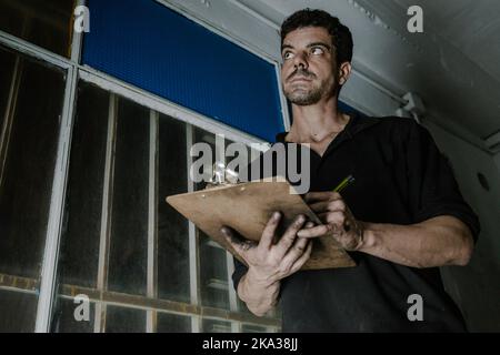 Technician checking paperwork in car service station Stock Photo