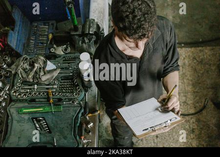 Technician checking paperwork in car service station Stock Photo