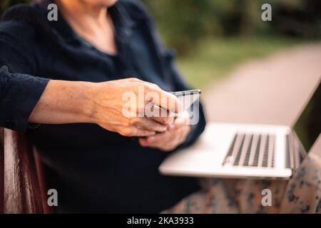 Mature business woman using smart phone and laptop computer in park Stock Photo