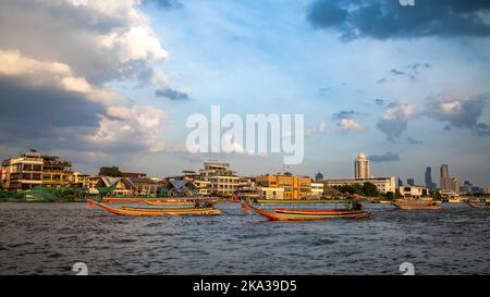 Traditional colourful long tail boats on the Chao Phraya river opposite Wat Arun in the heart of Bangkok, Thailand. Stock Photo