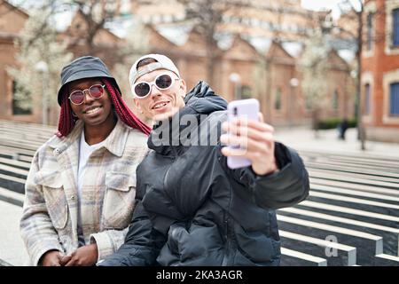 multiethnic couple using phone taking selfie, on the street Stock Photo