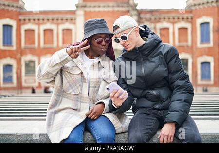 Multiethnic couple using phone taking selfie, on the street Stock Photo