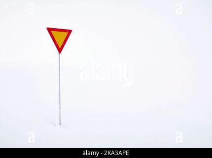 Yield sign located on snowy field Stock Photo