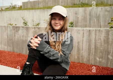 Cute girl sitting on gravel ground Stock Photo