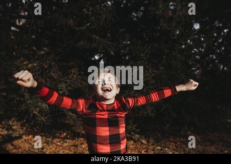 Young boy jumping for joy in christmas pajamas outdoors Stock Photo